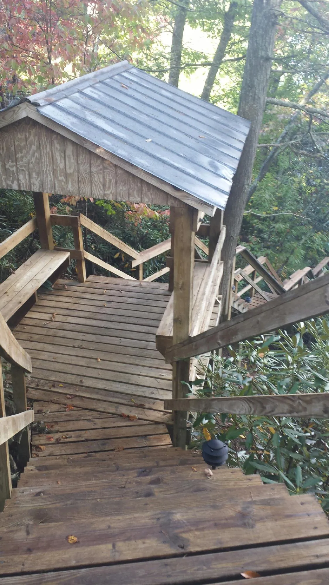 Metal roofed shelter over wooden steps on a wooded walkway — Skylight Repair & Installation work by our crew in Glencoe